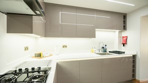 A modern kitchen with a gas stove, white countertops, and grey cabinets. - Hazel Lodge (Reading)