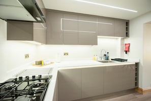 A modern kitchen with a gas stove, white countertops, and grey cabinets. - Hazel Lodge (Reading)