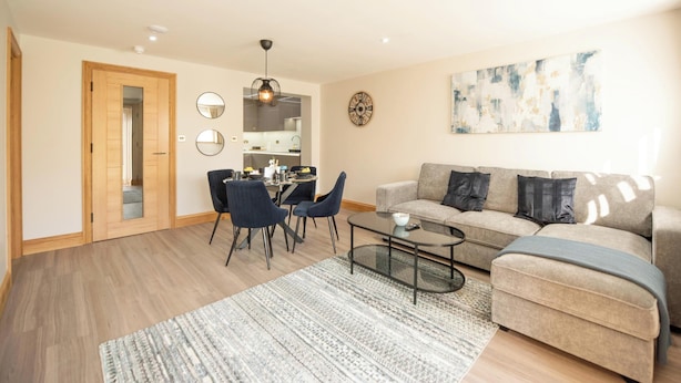 A modern living room with a sofa, coffee table, and dining area. - Hazel Lodge (Reading)