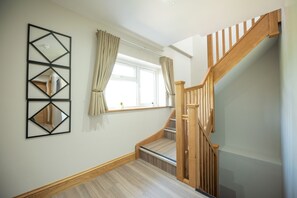 Un escalier avec des rampes et une main courante en bois, menant à l’étage supérieur.