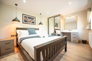 A bedroom with a bed, bedside tables, a dresser, a mirror, and a painting on the wall.