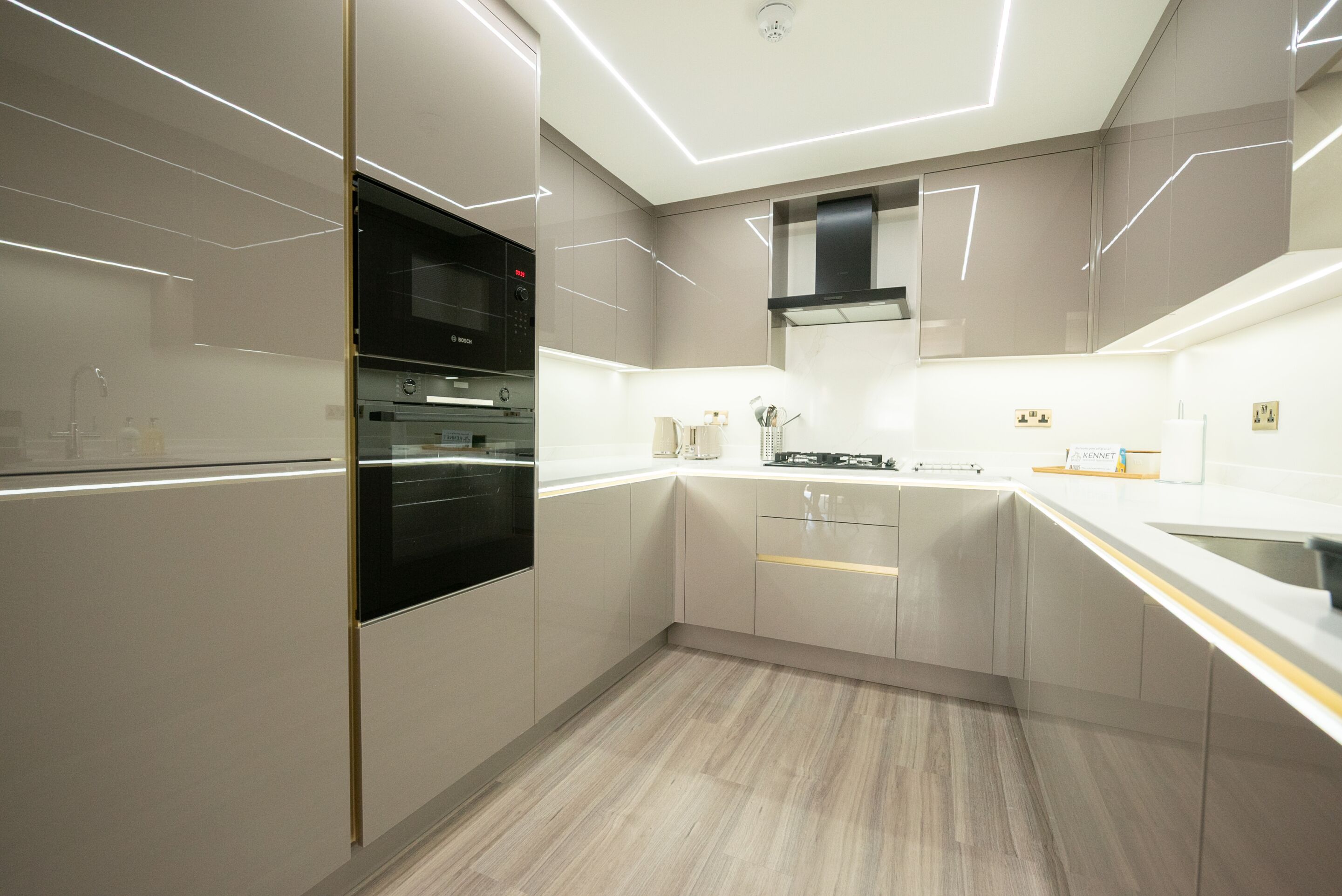 A modern kitchen with a built-in oven, microwave, and stainless steel range hood.