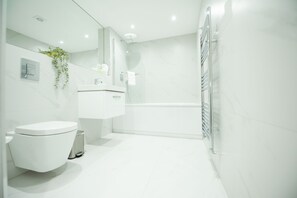 Un baño moderno con inodoro, lavabo, espejo y ducha.