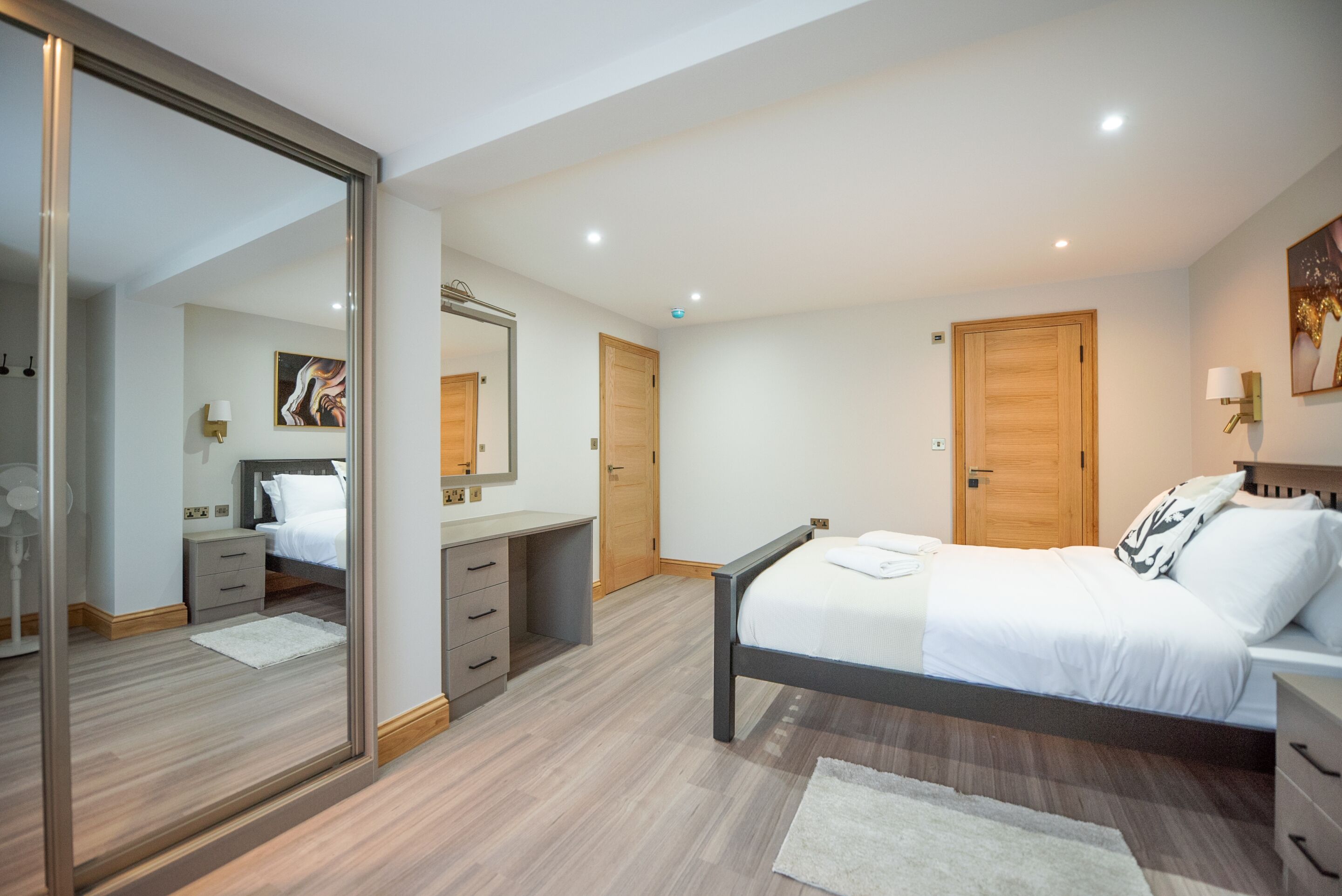 Un dormitorio con cama, cómoda, espejo y puerta.