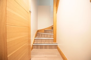 A wooden staircase with a handrail, leading to a landing.