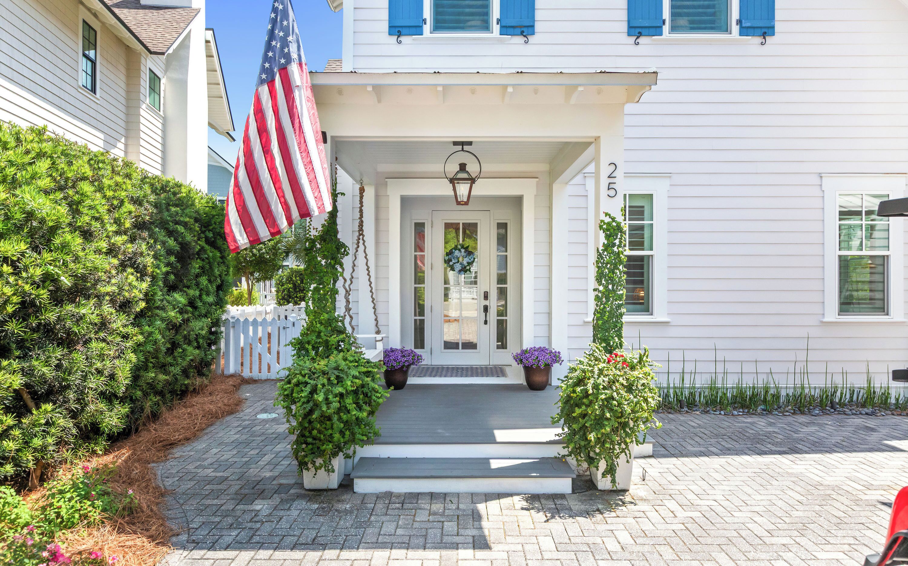 A white house with a front porch, an American flag, and a wreath.