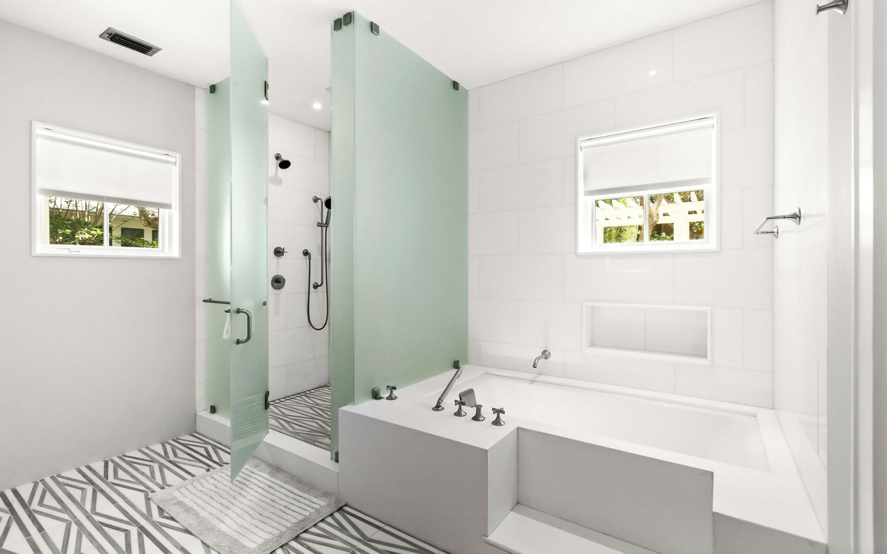 Une salle de bain moderne dotée d’une douche à parois de verre, d’une baignoire et d’un meuble-lavabo avec un miroir.