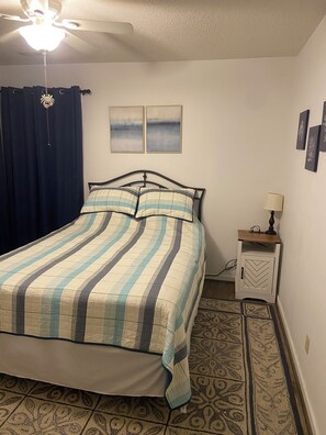 A bedroom with a bed, a nightstand, a lamp, a ceiling fan, and artwork on the wall. - Quiet Calabash neighborhood convenient to everything (Calabash)