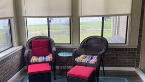 A sunroom with wicker furniture, a small table, and a blue rug. - Quiet Calabash neighborhood convenient to everything (Calabash)