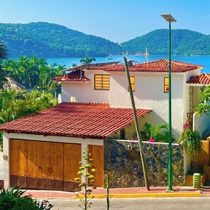 Ein Küstenhaus mit rotem Ziegeldach, einer Steinmauer und einer Holztgarage.