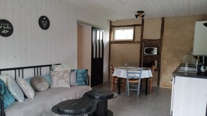 Une pièce confortable comprenant un lit, une table à manger, des chaises, un petit coin cuisine avec un four à micro-ondes et un ventilateur de plafond.