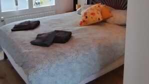 Makuuhuone, jossa on sänky, kattovalaisin ja ikkuna, jossa on verhot.