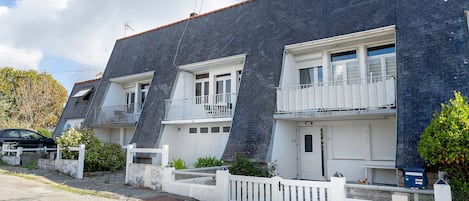 A row of townhouses with white balconies, a gravel driveway, and a blue mailbox.