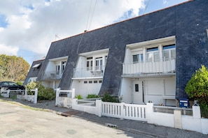 A row of townhouses with white balconies, a gravel driveway, and a blue mailbox. - Apartment 50 m from the Beach (Audierne)