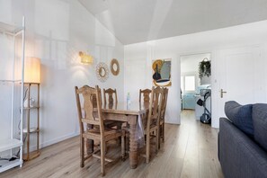 Un comedor con una mesa y sillas de madera, una lámpara y decoración en la pared.