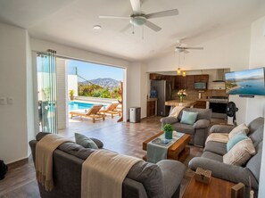 Ein modernes Wohnzimmer mit Pool, Küche und Essbereich.