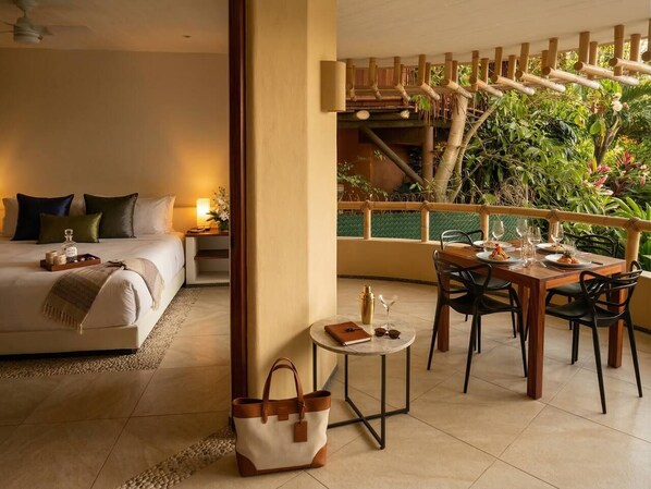 Una habitación de hotel con cama, mesita de noche y un área de comedor con sillas y mesa.