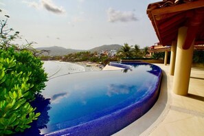 Una piscina con vistas a una playa y montañas al fondo.