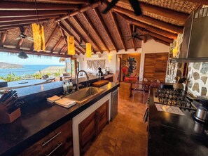 A kitchen with a large island, a dining area, and a view of the ocean.