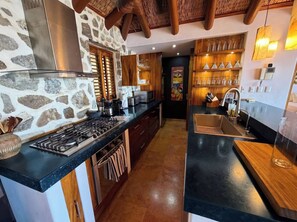 A modern kitchen with a stone wall, wooden cabinets, and a black countertop. - Adults only Luxe 3br La Ropa Oasis w/ ccean view (Zihuatanejo)