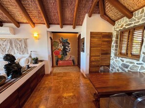 A hallway with a wooden ceiling, a stone wall, and a dining area with a table and chairs. - Adults only Luxe 3br La Ropa Oasis w/ ccean view (Zihuatanejo)