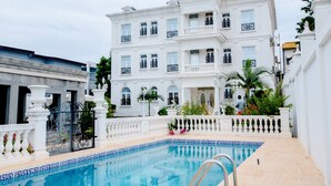 A white building with a pool, balconies, and a gated entrance. - Hôtel Chateau Blanc  (Yamoussoukro)