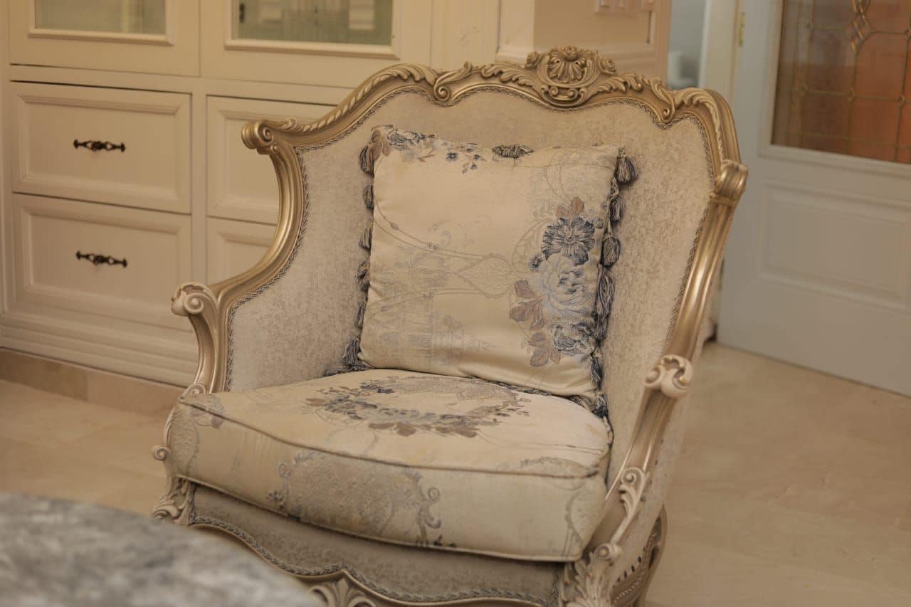 A vintage-style chair with ornate detailing and floral upholstery.