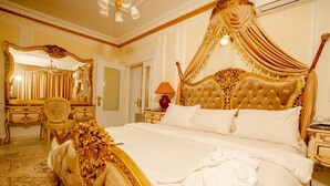 A luxurious bedroom with a four-poster bed, a large ornate mirror, a chandelier, and a classic chandelier. - Hôtel Chateau Blanc  (Yamoussoukro)