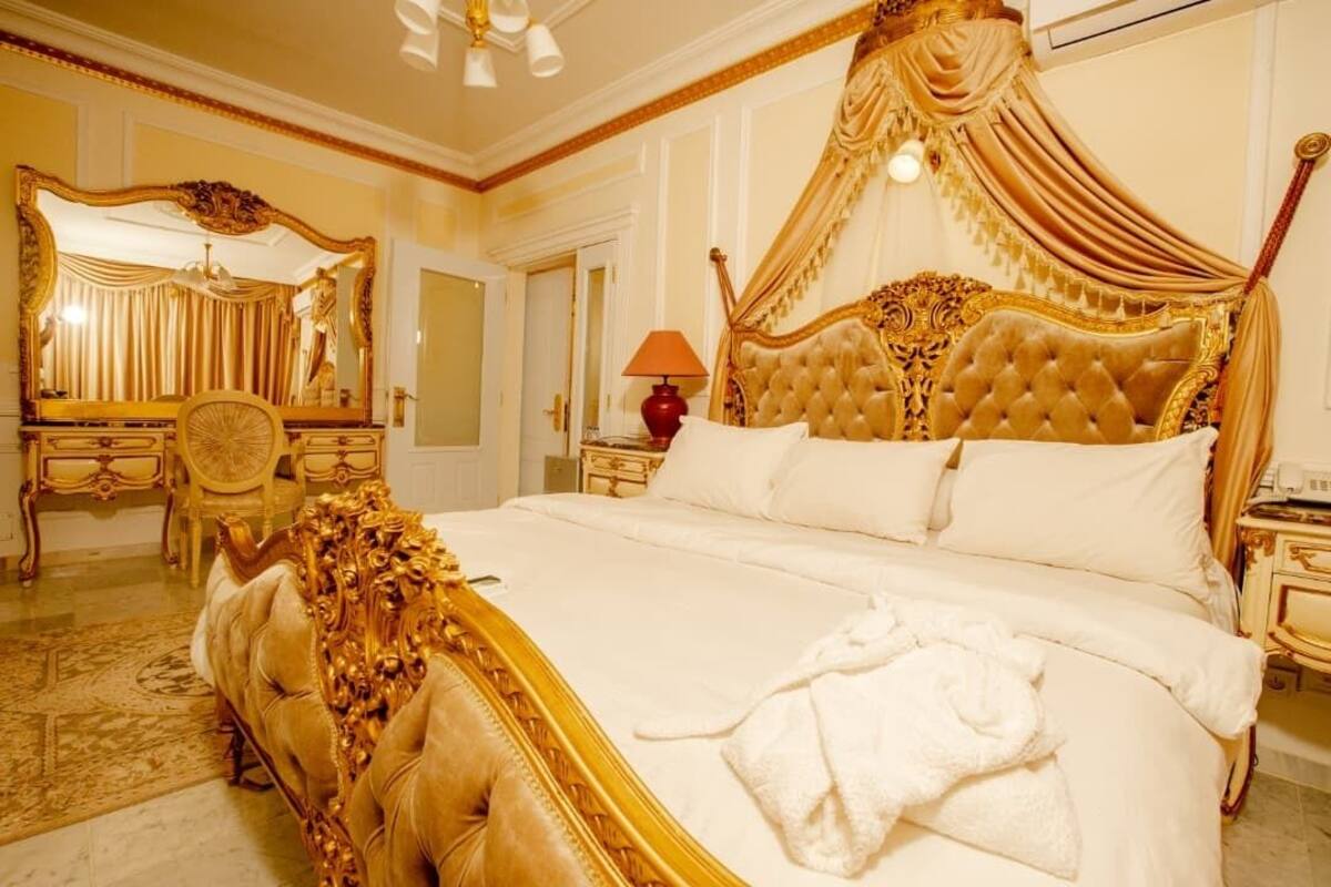 A luxurious bedroom with a four-poster bed, a large ornate mirror, a chandelier, and a classic chandelier.