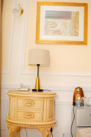 Une pièce comprenant une coiffeuse de couleur crème, une lampe, un tableau encadré, un téléphone et une machine à café.