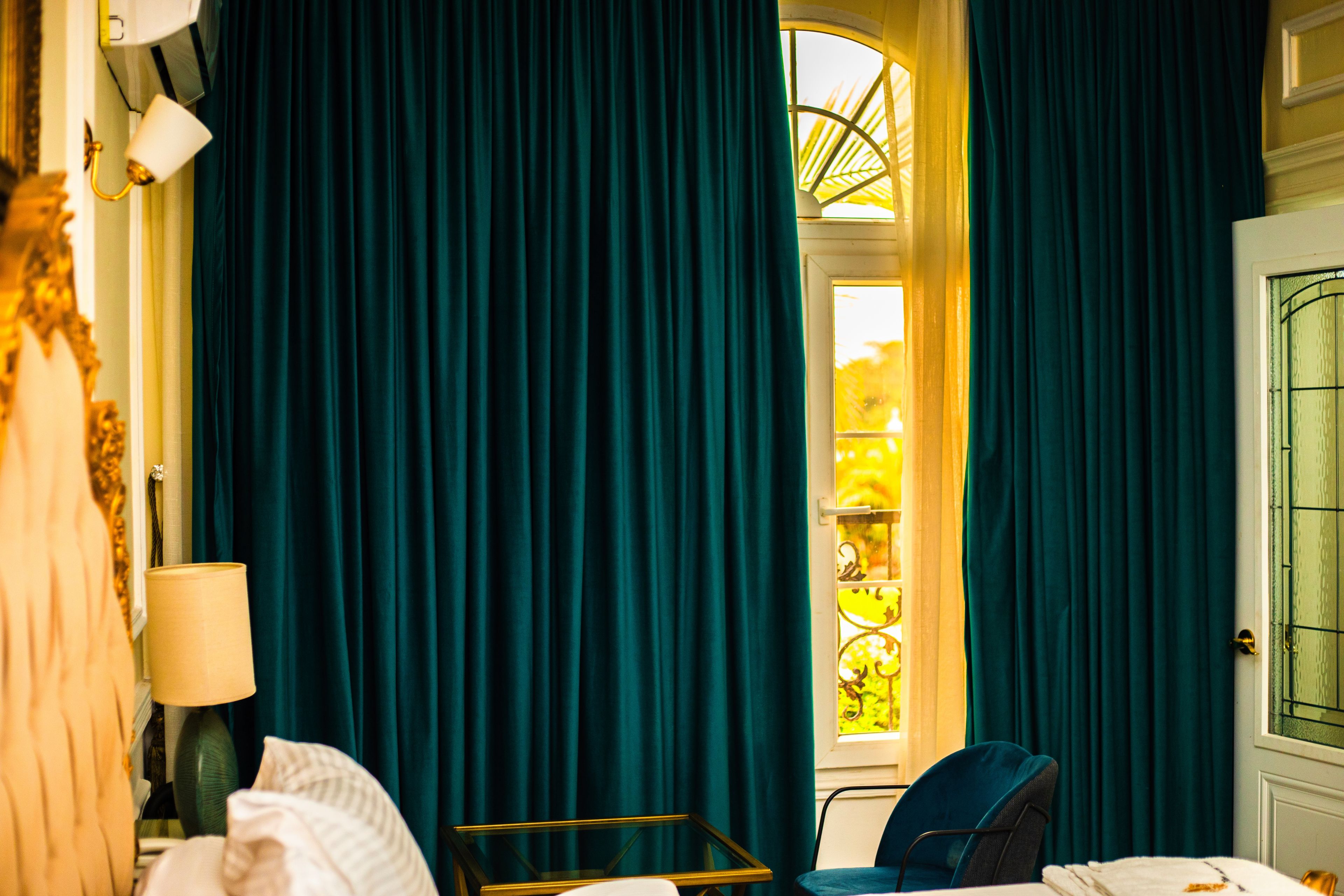 A room with a bed, a chair, a table, and curtains.