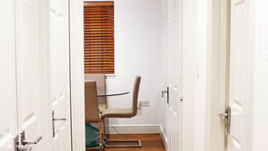 A narrow hallway with wooden flooring, white doors, and a window with blinds. - Comfortable, modern 2 bed apartment in the heart of the Old Town (Hemel Hempstead)