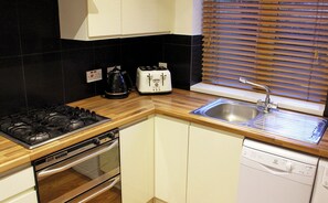 A compact kitchen with a gas stove, toaster, sink, and dishwasher. - Comfortable, modern 2 bed apartment in the heart of the Old Town (Hemel Hempstead)