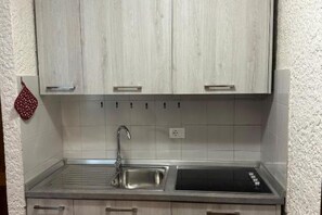 A kitchen with a stainless steel sink, a faucet, and light-colored cabinets.