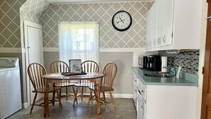 A compact kitchen with a dining area, a clock, and a washing machine.