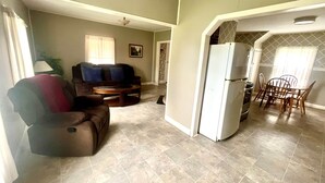 A living room with a sofa, a coffee table, and a dining area with chairs and a table.