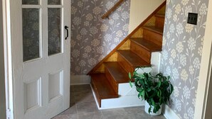 A staircase with a wooden handrail, a potted plant, and a door with frosted glass panels.