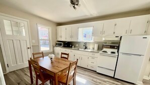 A kitchen with white cabinets, a wooden dining table, and a microwave.