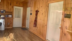A wooden interior with a water dispenser, a door with a sign, and a plaid dress hanging on the wall.