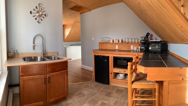Une cuisine équipée d’un évier, de meubles de rangement en bois, d’un four à micro-ondes et d’un grille-pain.