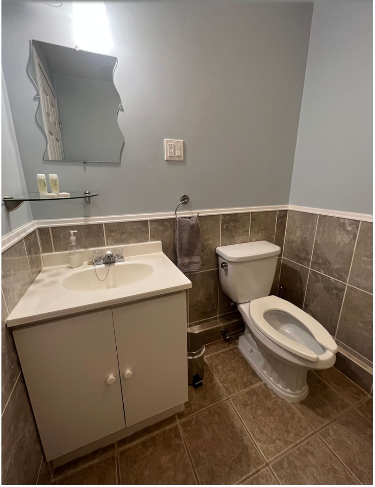 A bathroom with a sink, toilet, and mirror.