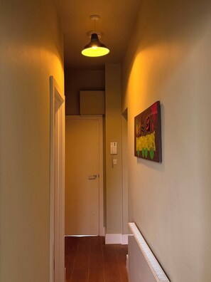 A hallway with a door, a wall-mounted telephone, and a painting. - One bed flat five mins from tube, Islington (London)