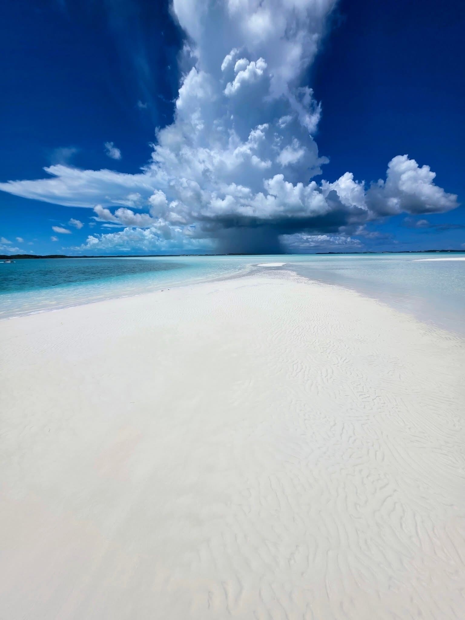 A beach with white sand and clear blue water.