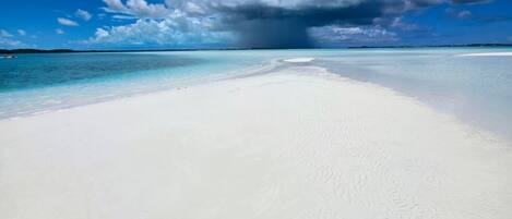 A beach with white sand and clear blue water.