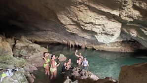 Un grupo de personas en una poza natural dentro de una cueva, con formaciones rocosas y estalactitas.