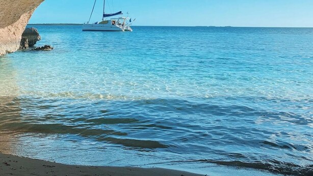 Un bote bajo una formación rocosa natural junto al mar.