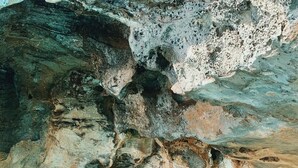 Una cueva natural con agua cristalina en el fondo y paredes rocosas.