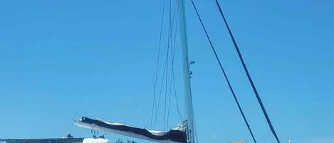 A large yacht with multiple decks and a tall mast, floating on calm water.