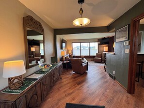 A hotel room with a wooden floor, a large mirror, a dining area with a table and chairs, and a view through the window. - Green Bay Original Across From Lambeau Field: Where Every Stay Becomes Tradition (Green Bay)