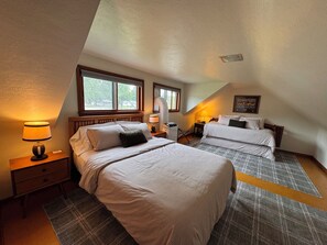 A bedroom with two beds, a nightstand, a lamp, and a window. - Green Bay Original Across From Lambeau Field: Where Every Stay Becomes Tradition (Green Bay)